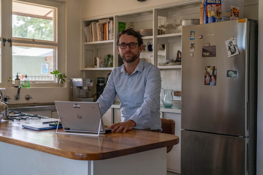 A man sits at a computer in his house. 