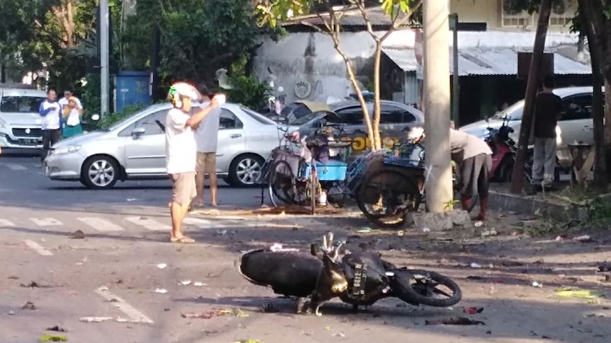 A motorcycle lies on a road strewn with debris.