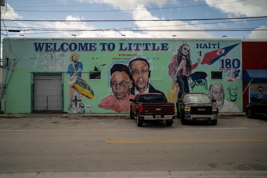A sign with Welcome To Little Haiti written on it and portraits of people.