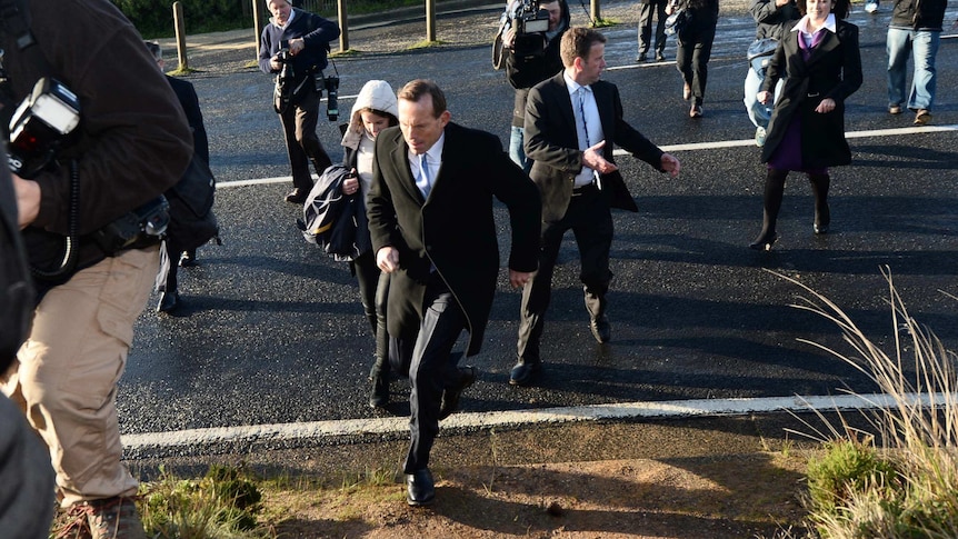 Tony Abbott, surrounded by media, runs across the Great Ocean Road in Victoria