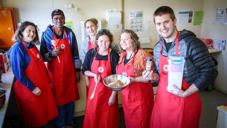 A group of parents smile for the camera as they stand in the kitchen