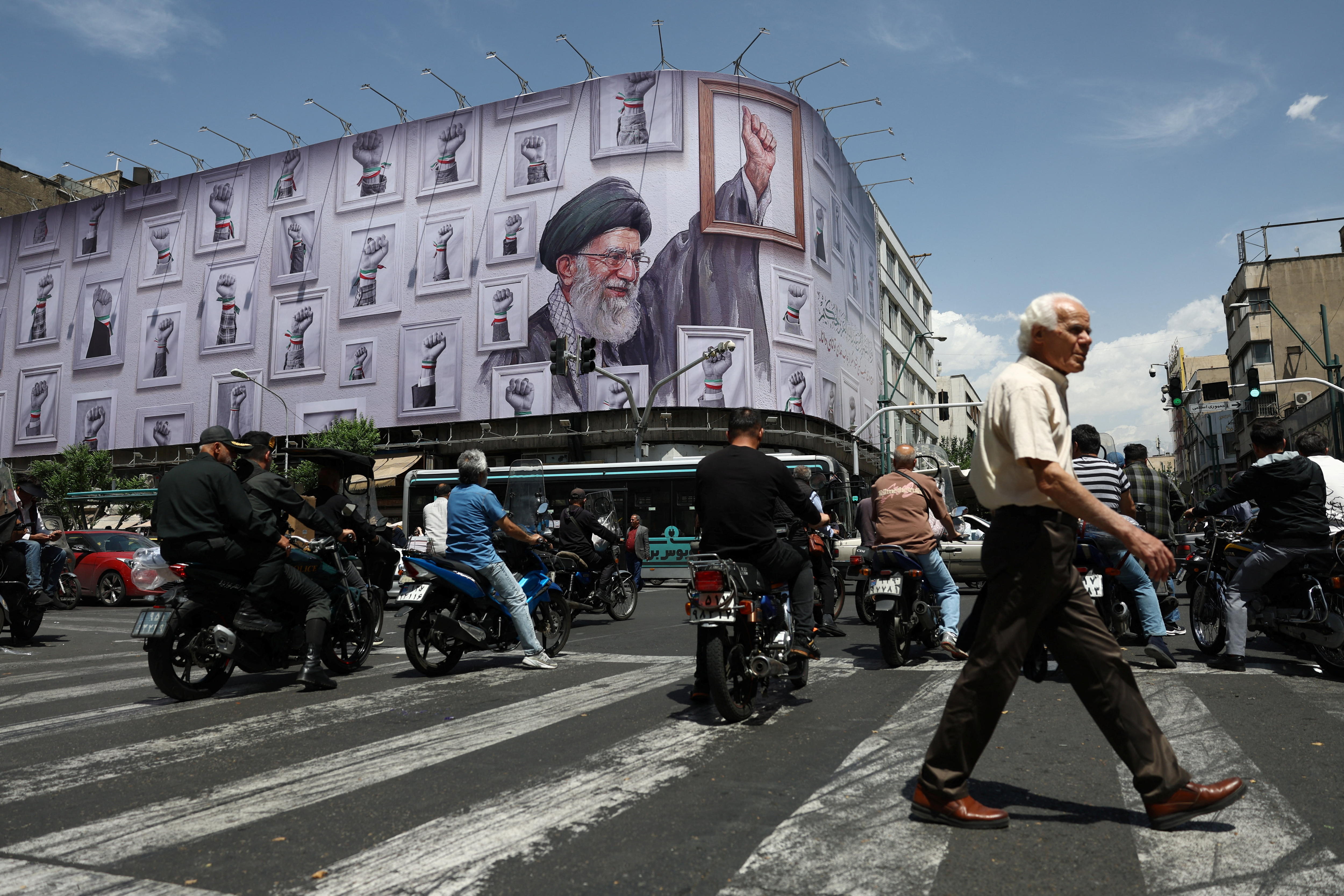 A mural showing Ayatollah Ali Khamenei raising his fist, and dozens of other raised fists, on a building in Tehran.