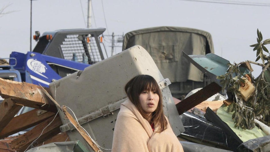 Stunned woman stands amid the debris of Japan quake