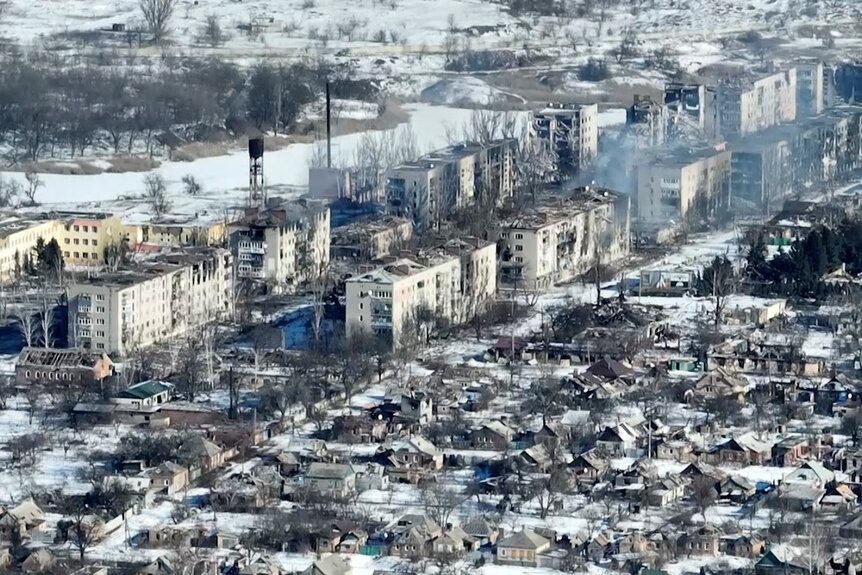 Aerial vision of snow-covered town charred by missiles from the war.