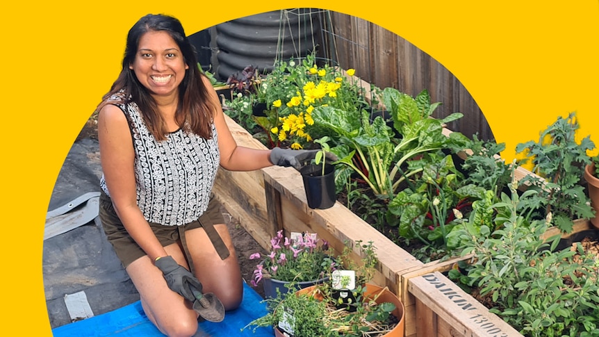 Woman kneeling in her courtyard, holding a pot, planting veggies and flowers, adding colour to her garden.