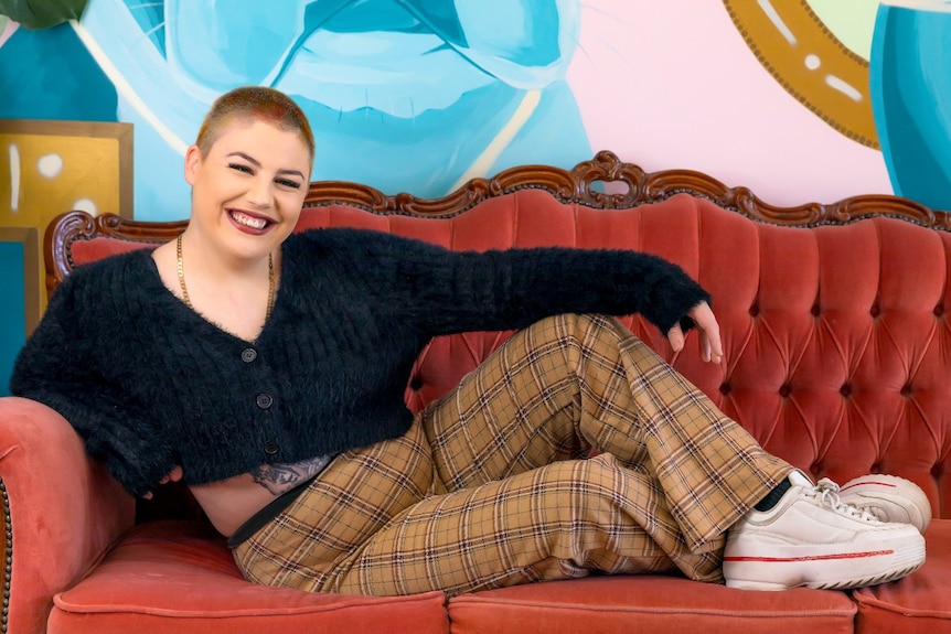 A smiling woman lying on a couch.