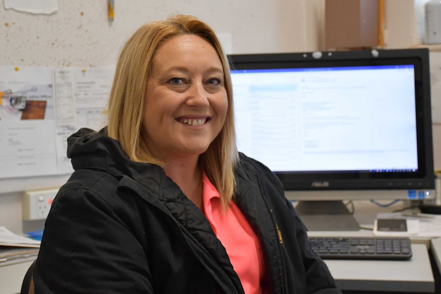 A lady with blonde hair sits in an office.