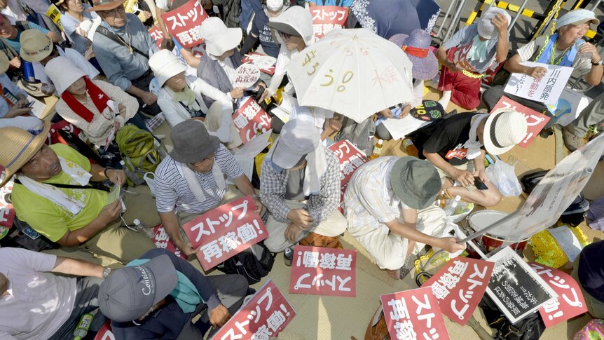 Protesters stage a sit-in in front of an entrance gate of Kyushu Electric Power's Sendai nuclear power station in Satsumasendai