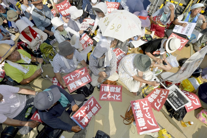 Protesters stage a sit-in in front of an entrance gate of Kyushu Electric Power's Sendai nuclear power station in Satsumasendai