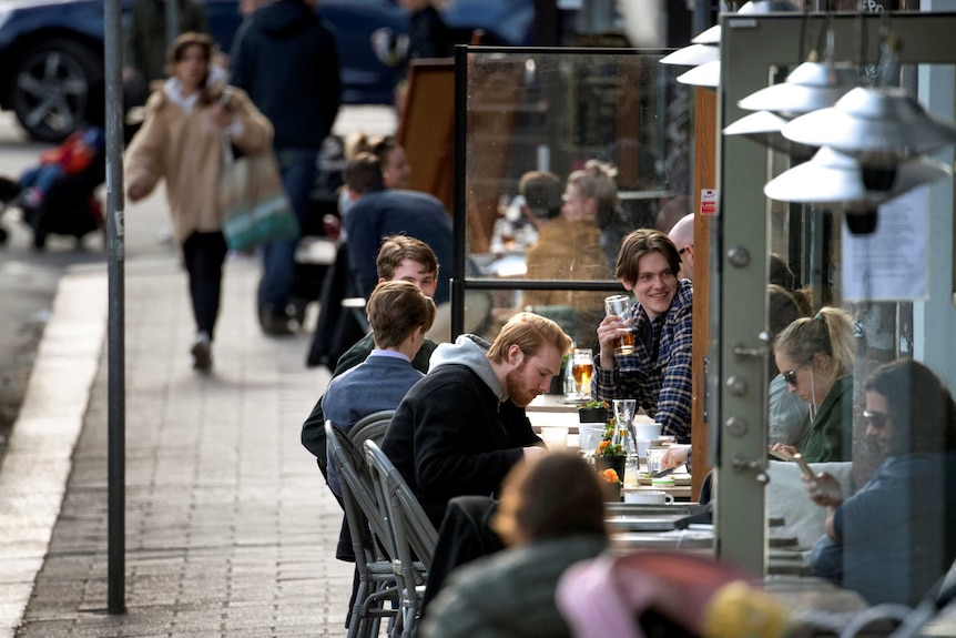 Swedes sit at tables outside.