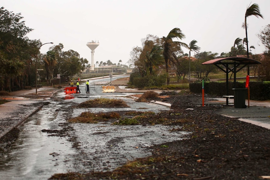 Workers clean up a street inundated with water and debris