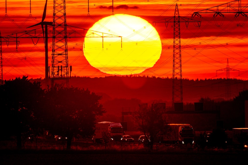 The sun rises above a highway. The sky is coloured red and yellow.