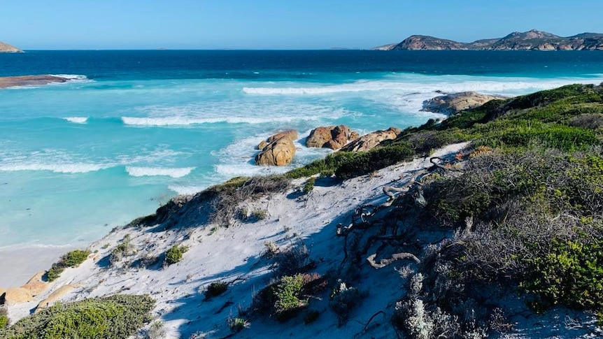 A sand dune, very blue water and islands in the background