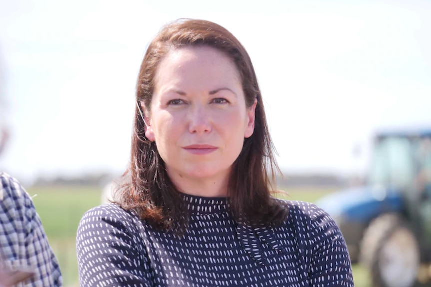 A dark-haired woman with a sober expression on her face.