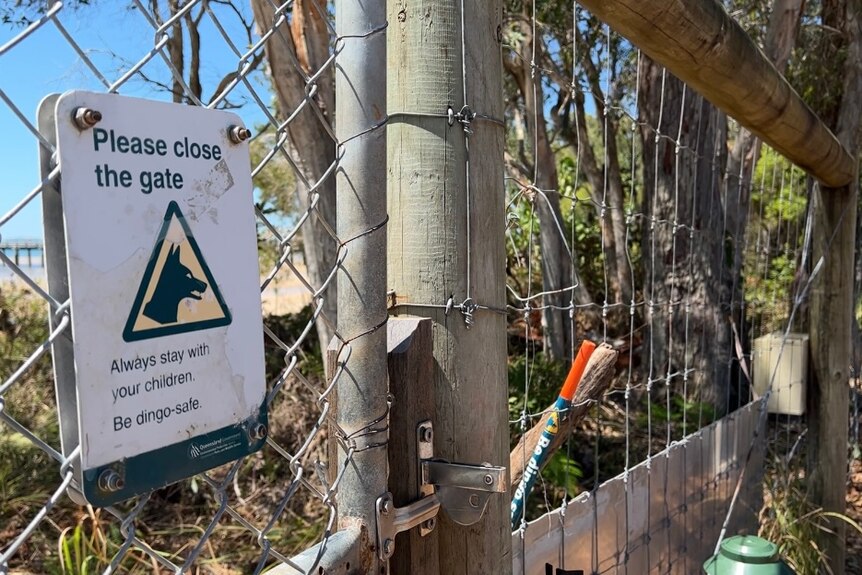 A sign warns visitor to be dingo-safe and close the gate. 