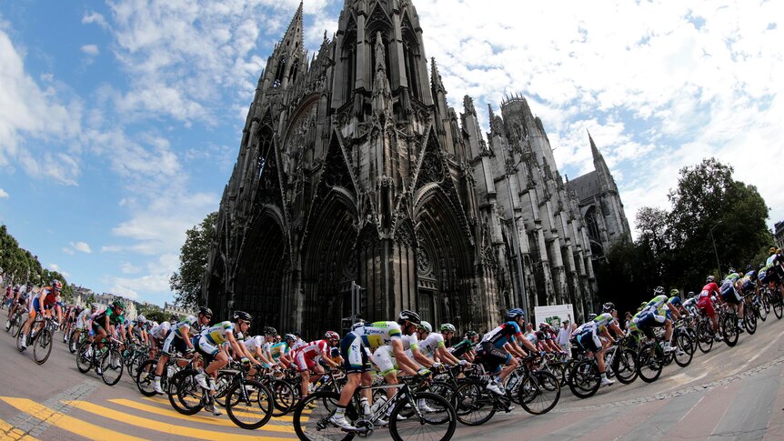 The peloton rides past Saint-Ouen Abbey during the Tour de France.