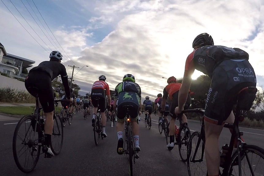 Rear shot of riders in a group riding through suburban streets