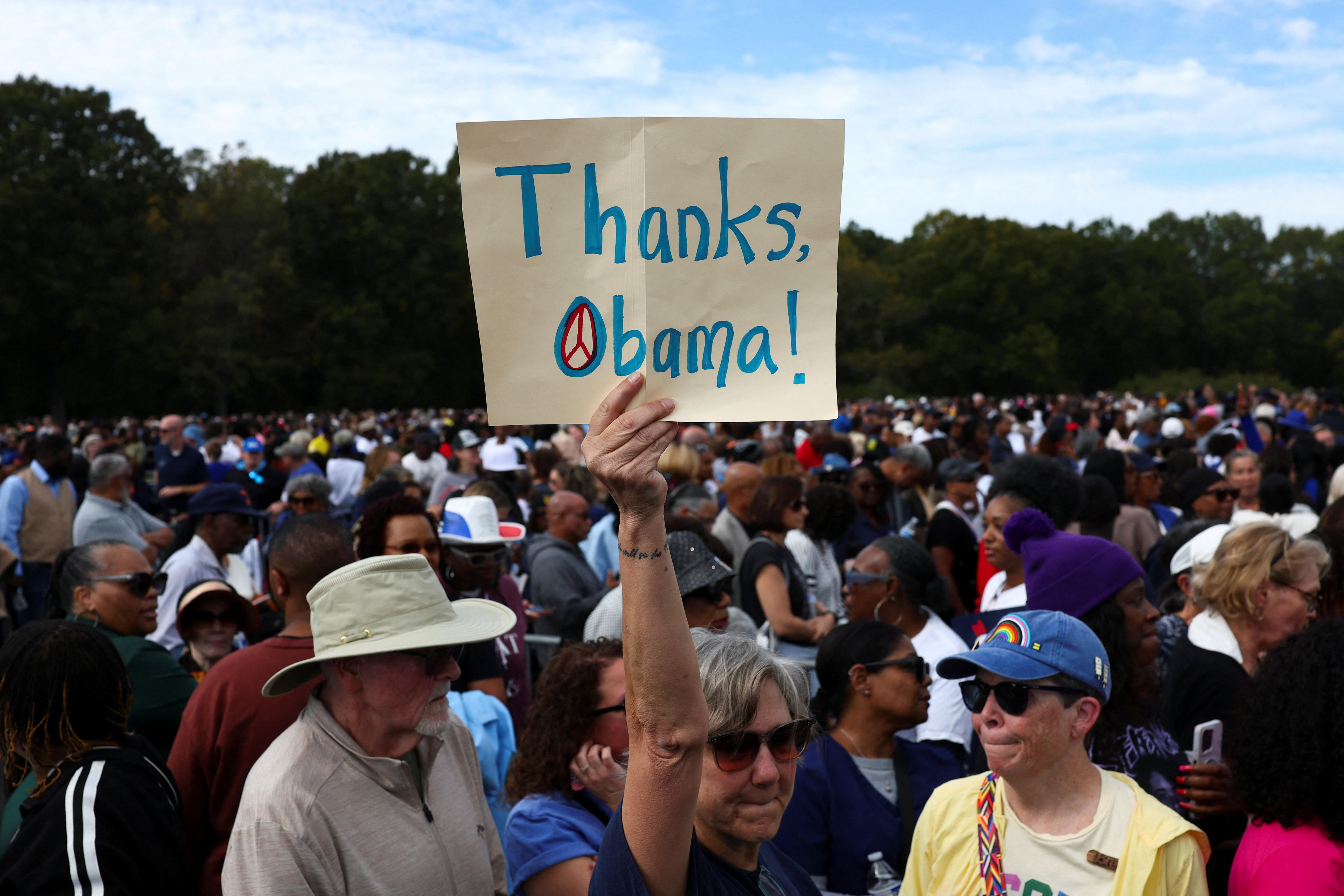 A Democrat supporter holds up a "Thanks, Obama" sign in a rally crowd
