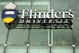 A Flinders University sign on a glass wall.