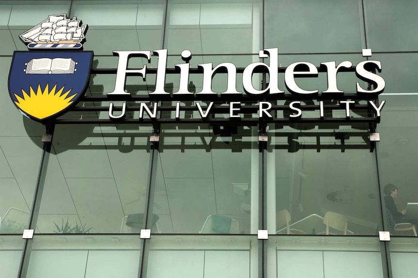 A Flinders University sign on a glass wall.