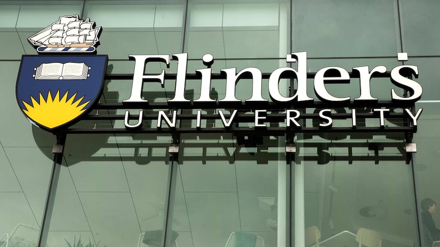 A Flinders University sign on a glass wall.