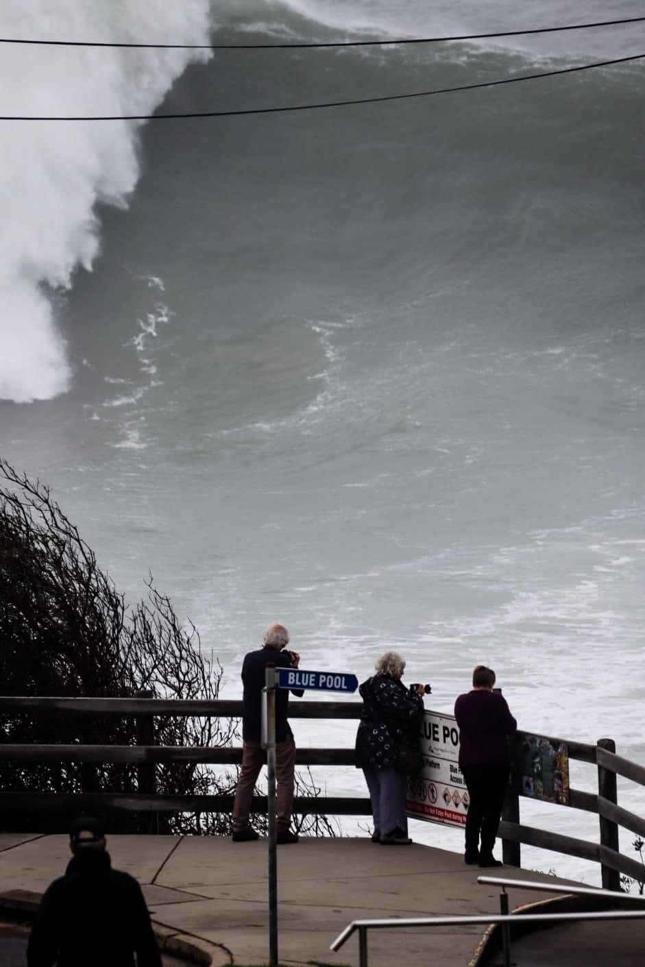 People at a lookout in Bermagui watch as a massive wave rolls in. 