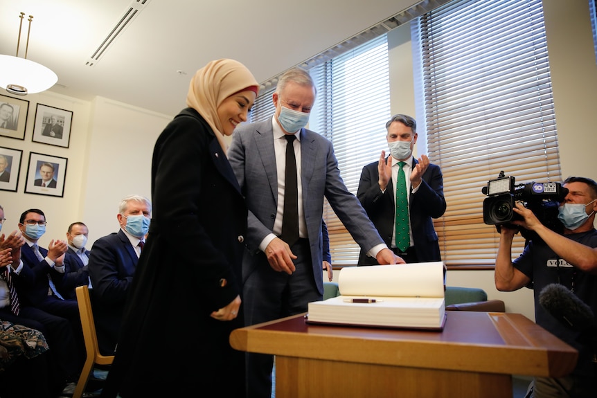 Anthony Albanese and Richard Marles stand alongside Fatima Payman as she signs the Labor roll