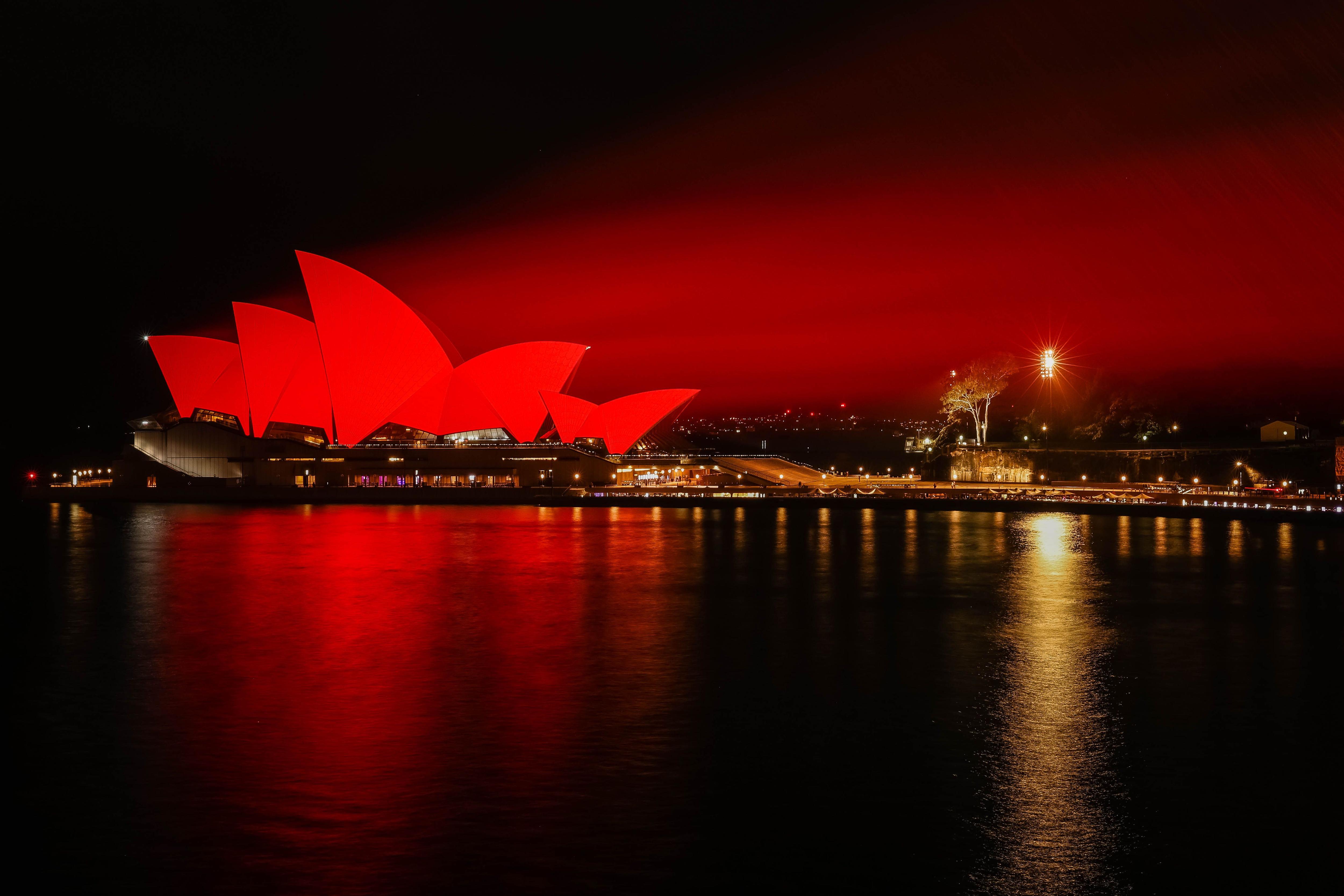 The Sydney Opera House bathed in red light at night. 