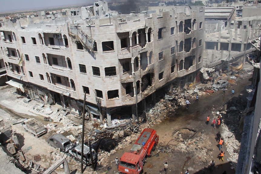 Syrian Civil Defence members gather at a site following air strikes.