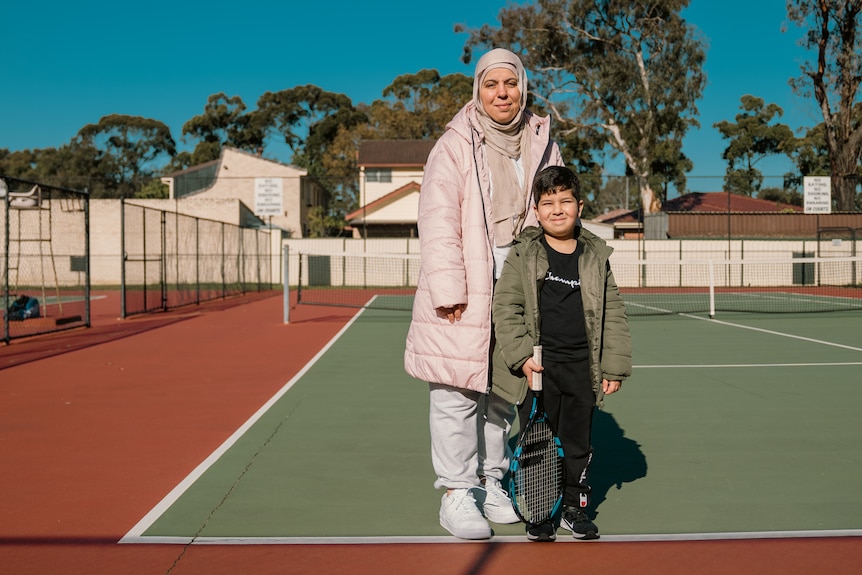 a woman and a small child standing on a tennis court