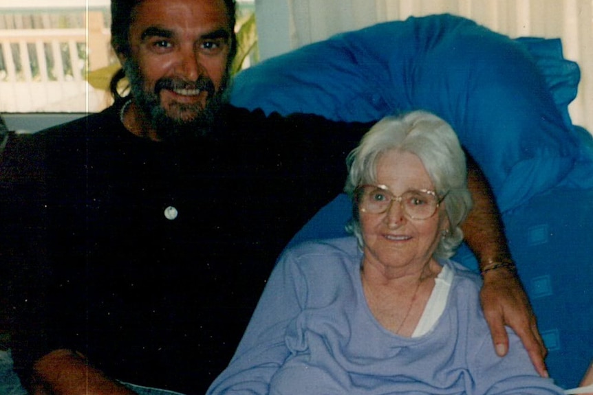 An Indigenous man with a ponytail and beard pictured with an older woman.