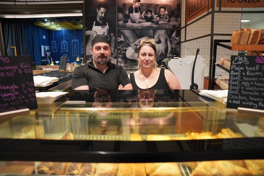 Woman and man standing behind counter at bakery.