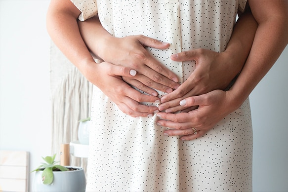 Couple holding the woman's pregnant tummy in a home setting