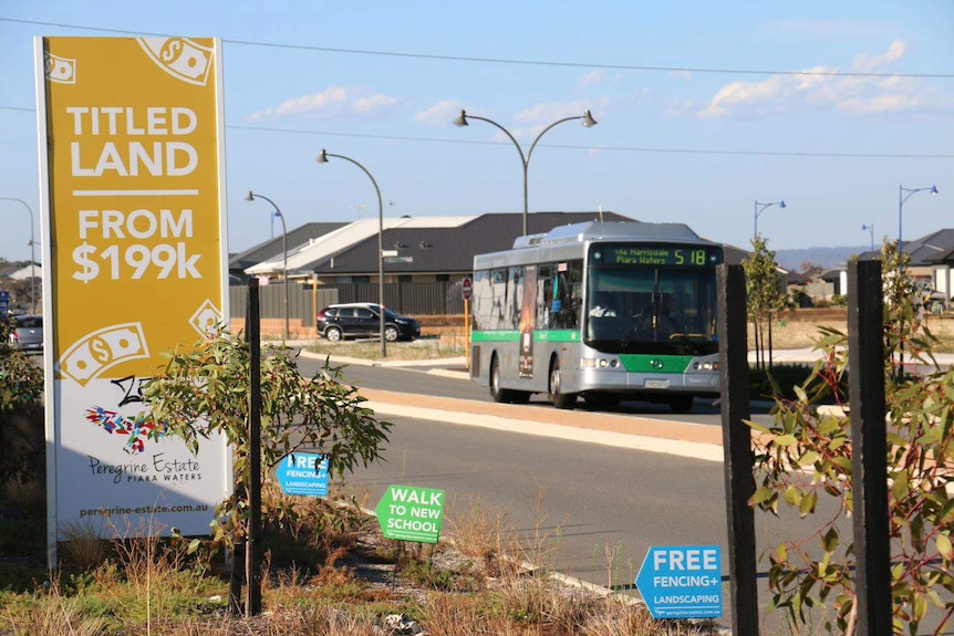 A bus and a land sale sign at a new housing estate.