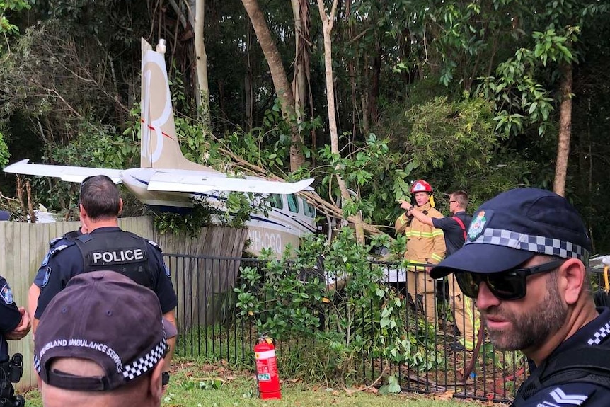 A light plane crashes into a fence and foliage in a backyard.