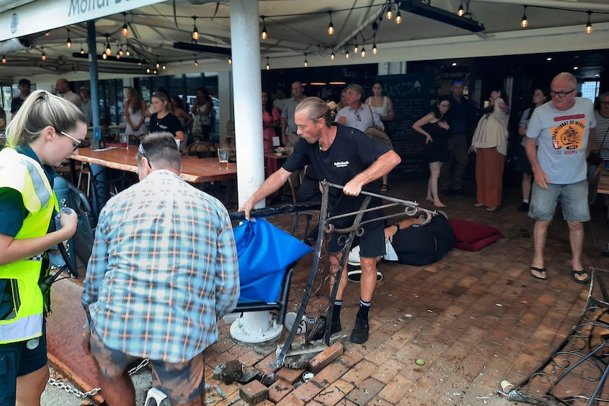 Les gens nettoient après qu'une voiture s'est écrasée dans le restaurant Moffat Beach Brewing Co sur Seaview Terrace à Moffat Beach.