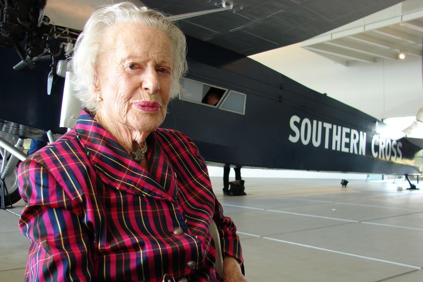 old woman in front of a plane