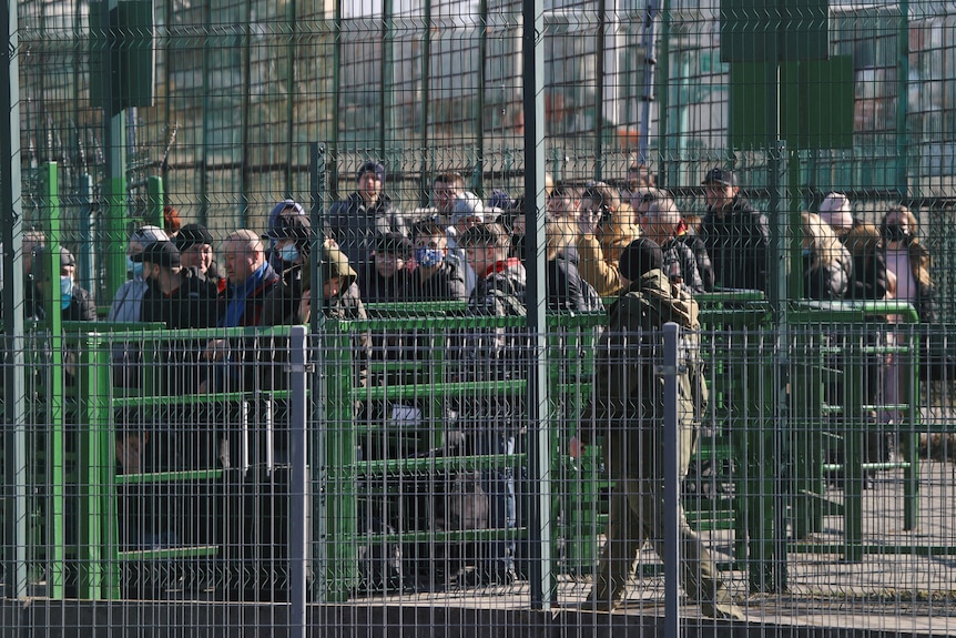 Les gens attendent derrière des clôtures