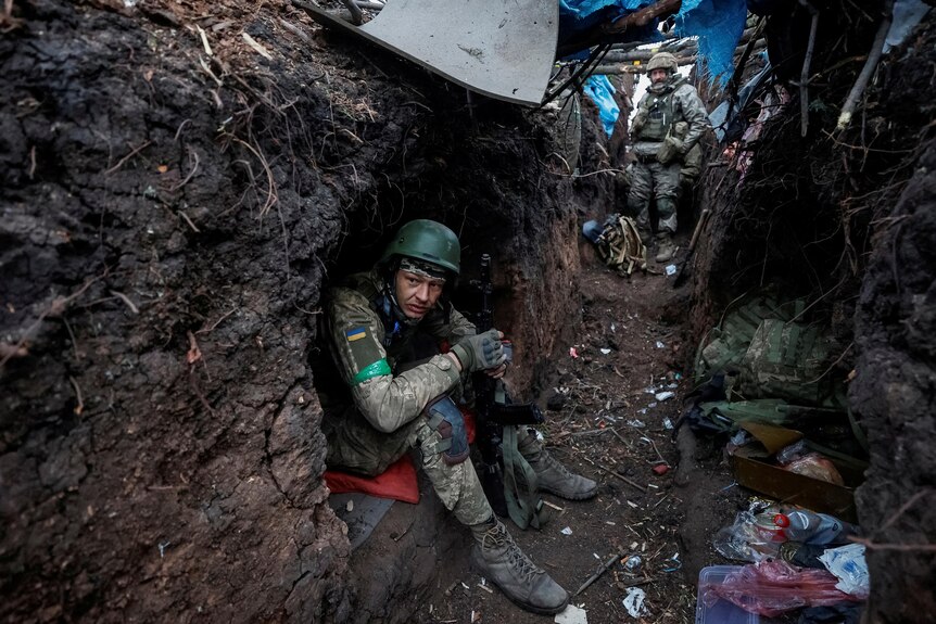 一个穿着军装和头盔坐在战壕里的人。