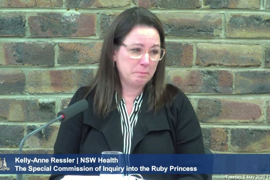 A woman cries as she sits being questioned at an inquiry