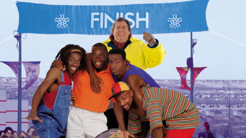 John Candy with four black actors who have their arms around each other and are standing behind a bobsled