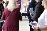 People hand out flyers at a polling booth.