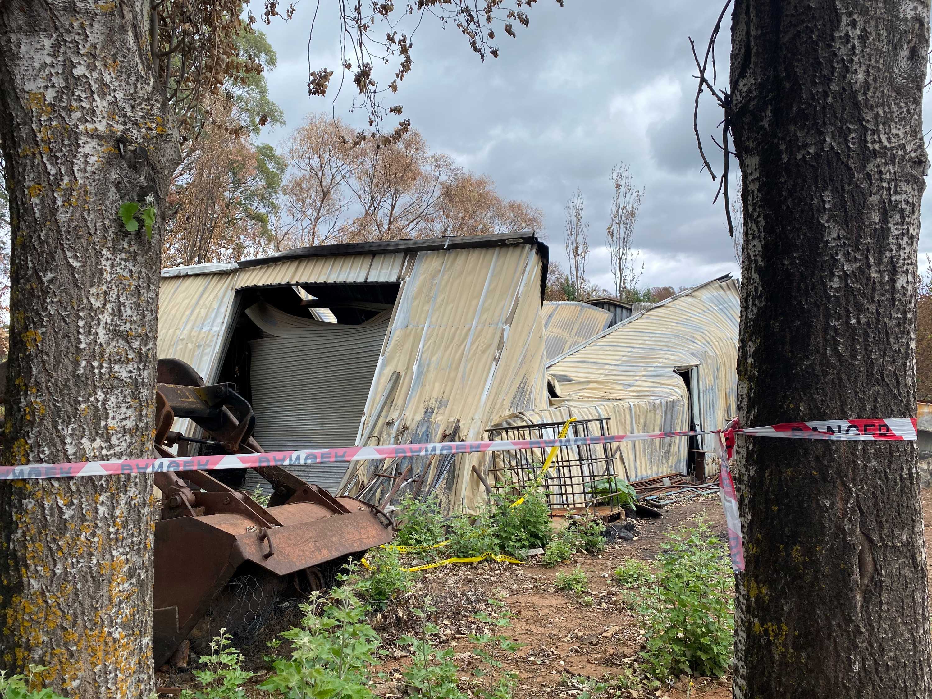 A shed that is twisted and flattened after being burnt by bushfire.