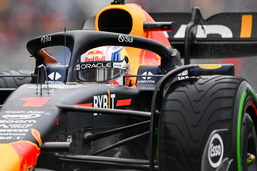 Max Verstappen in his Red Bull F1 car, on track, turning through a corner to the right as he races.