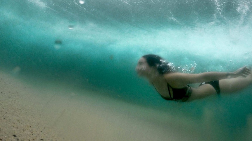 Underwater photo of a swimmer diving under a wave.