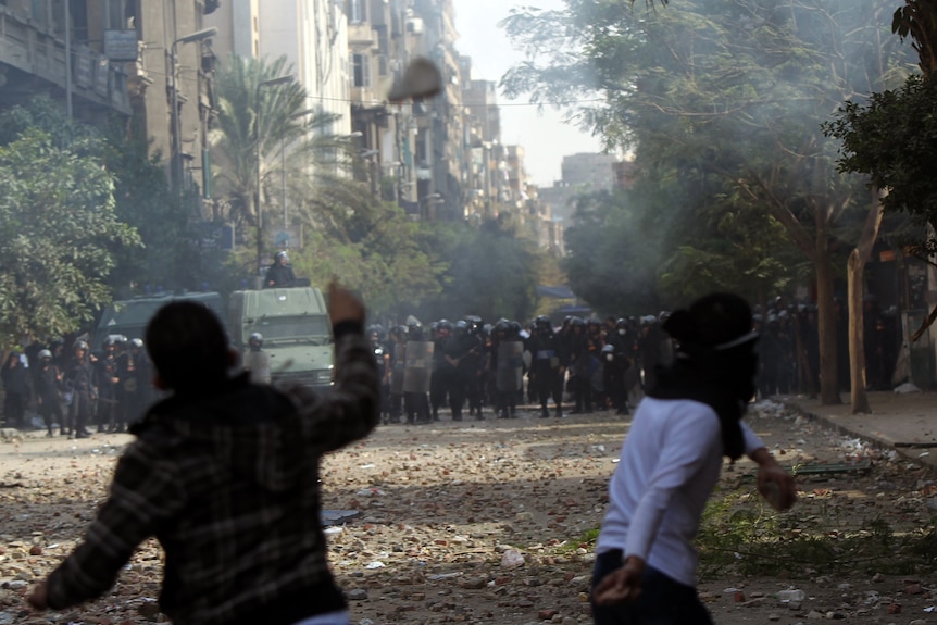 Egyptian protesters lob stones as they face off against riot police during clashes at Cairo's landmark Tahrir Square.