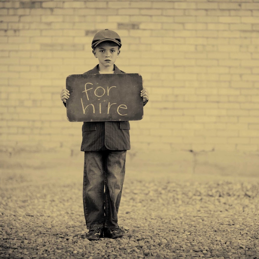 A young boy holding a sign “for hire’