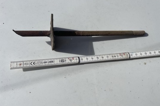 A rusty metal spike alongside a ruler