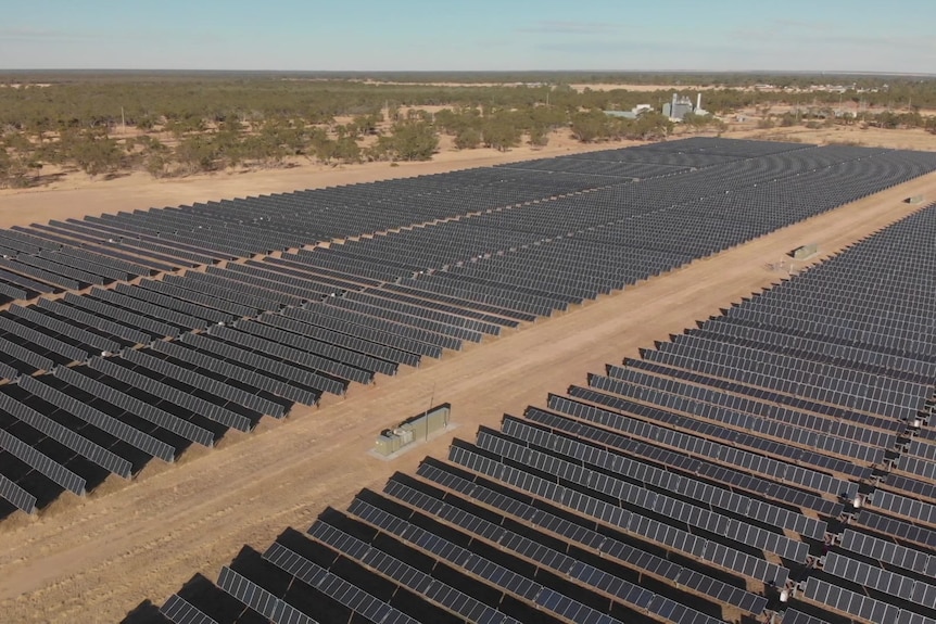 Aerial shot of hundreds of solar panels in a field.