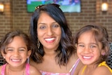 A woman smiling with two kids.